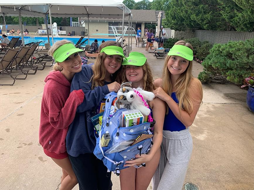 4 teenage kids at swim-a-thon holding a bag of fun.