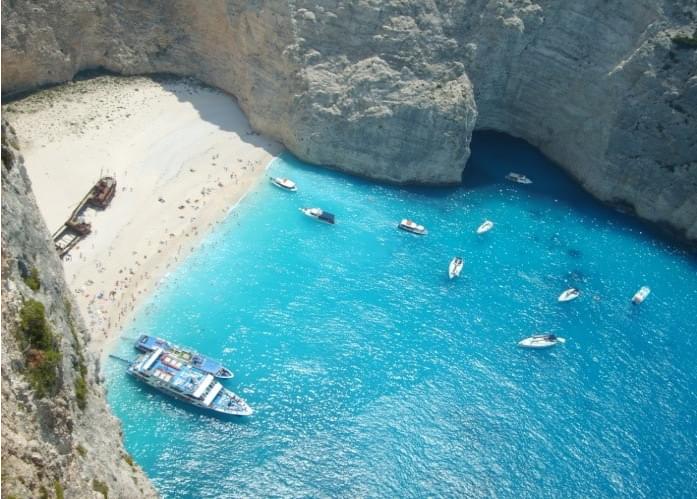 Overhead view of a gorgeous beach and pristine blue water and boats in Greece