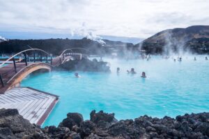 Iceland swimming area with people and steam emanating from the water.