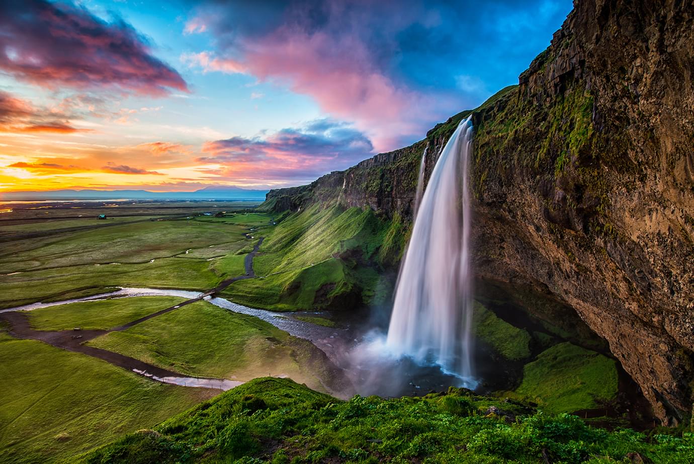 Iceland waterfall with a sunset in the distance
